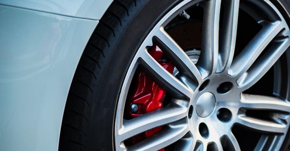 A semi-slick tire leaning diagonally up against the corner of a wall. It looks like a brand-new tire with a white rim.