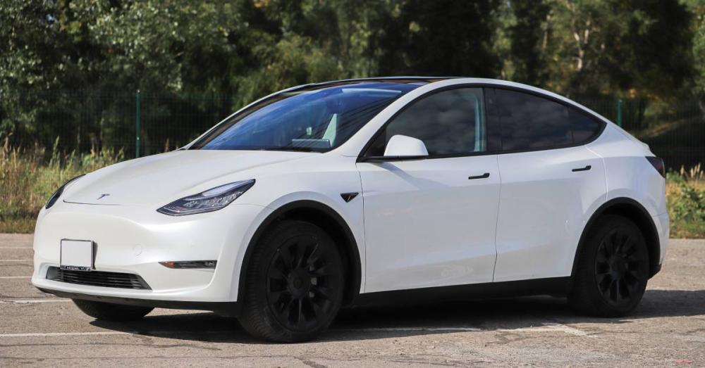 A white Tesla Model Y sitting in a parking lot. It isn't parked between the lines and is instead at an angle.