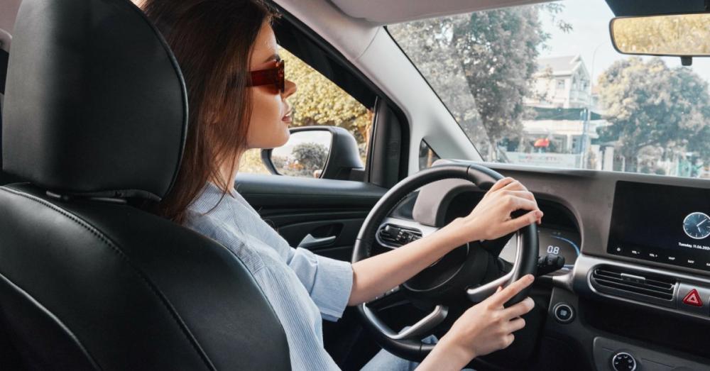 A woman carefully observing her surroundings while driving her car. She has both hands on the while while turning.