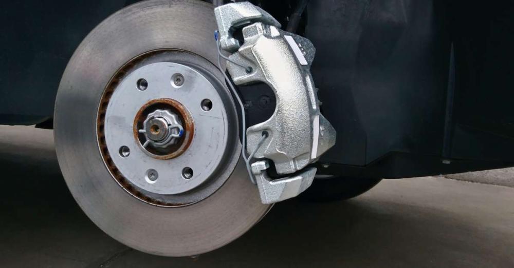 A close up of a car's brake system. The wheel has been removed so the brake pad and rotor are fully visible.