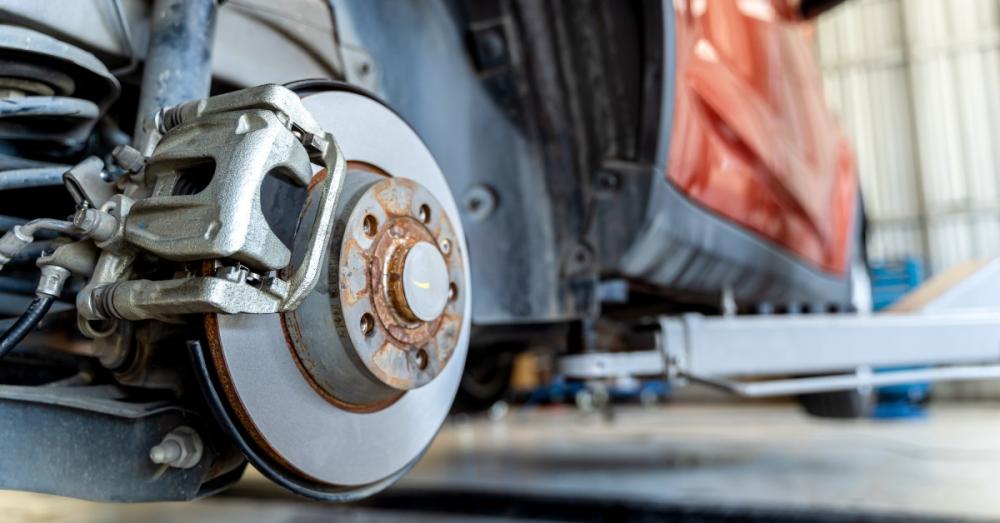 A closeup of the rear brake system of a car. The wheel has been removed, but the brakes and rotor are still attached.