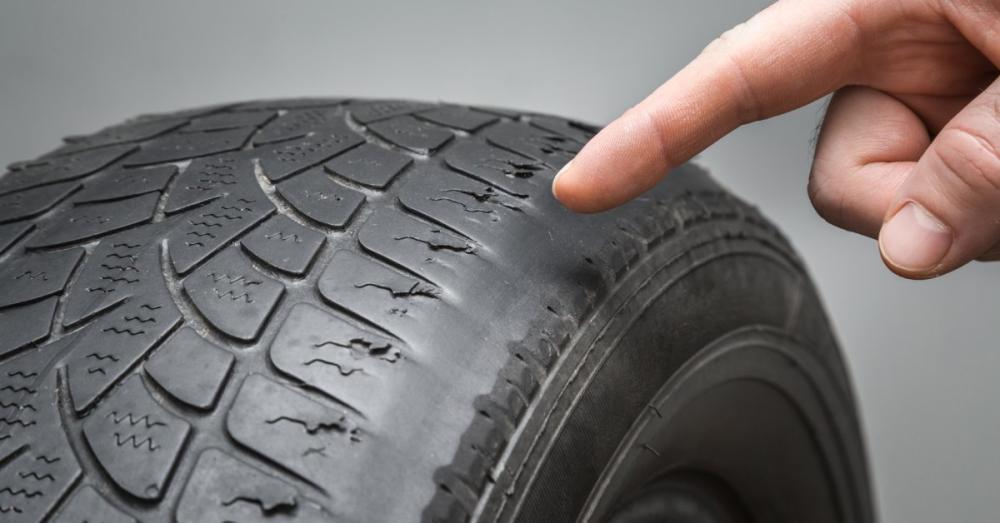 Someone pointing at the bald section of a tires. The tire is really worn down, but it's worse in that area.